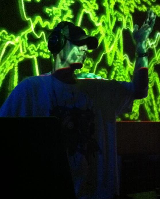 DJ Natural Nate® performing with hand raised under vivid green neon psychedelic backdrop